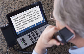 man on phone looking at captions on Hamilton Captel 2400 phone